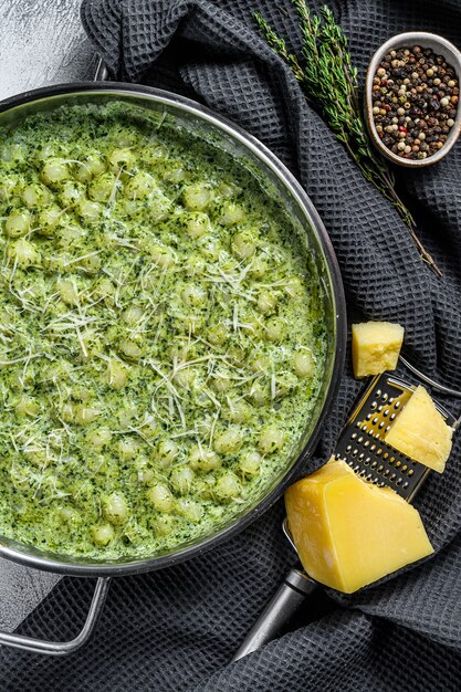 Gnocchi with basil spinach sauce. Italian potato paste. Gray background. Top view.