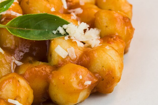 Gnocchi with juice sauce with grated cheese and basil served on the plate Closeup Selective focus