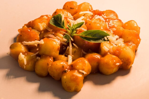 Gnocchi with juice sauce with grated cheese and basil served on the plate Closeup Selective focus