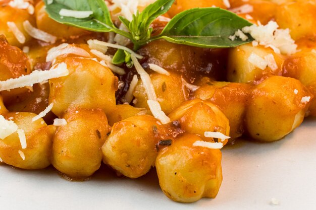 Gnocchi with juice sauce with grated cheese and basil served on the plateSelective focus Top view