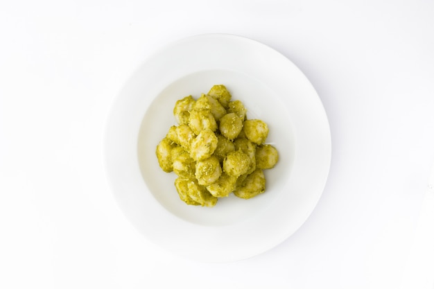 Gnocchi with pesto sauce in plate isolated top view