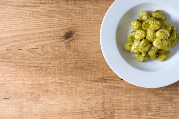 Photo gnocchi with pesto sauce in plate on wooden table