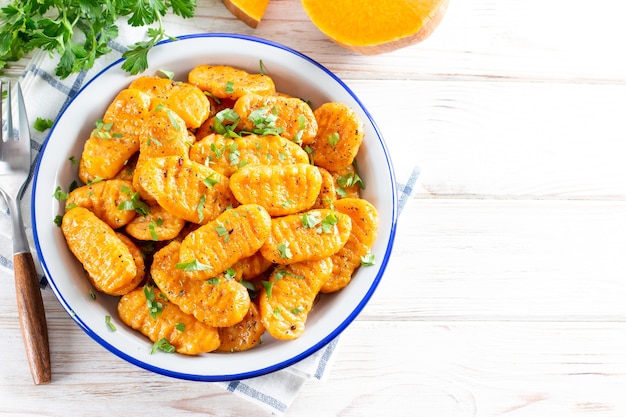 Gnocchi with a pumpkin on the plate. Italian dumplings with butter. Autumn meal. Top view, copy space