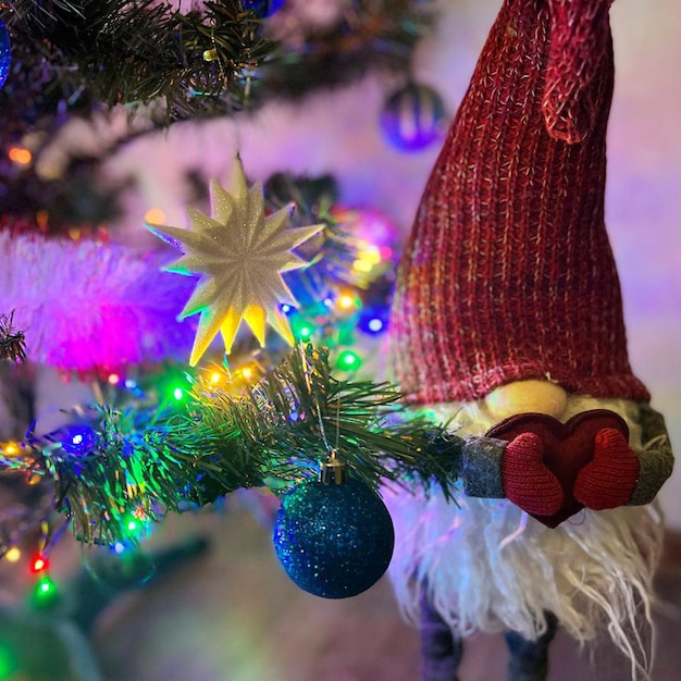 Gnome stands and holds a heart under the tree