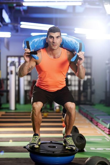 Go heavy or go home Shot of a young man working out with a sandbag at the gym