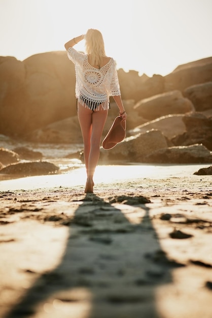 Go where you feel the most alive Rearview shot of a young woman standing on the beach