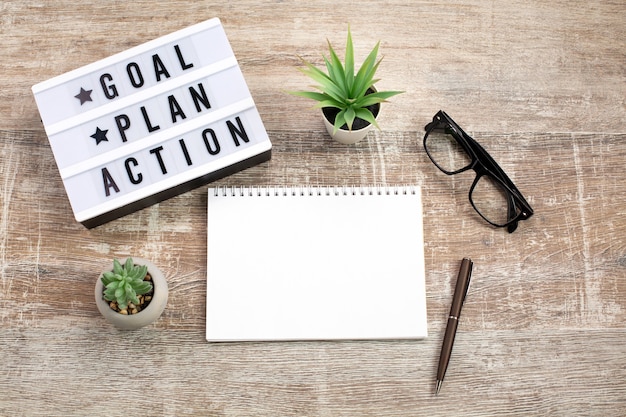 Goal, Plan, Action text on light box and Notebook