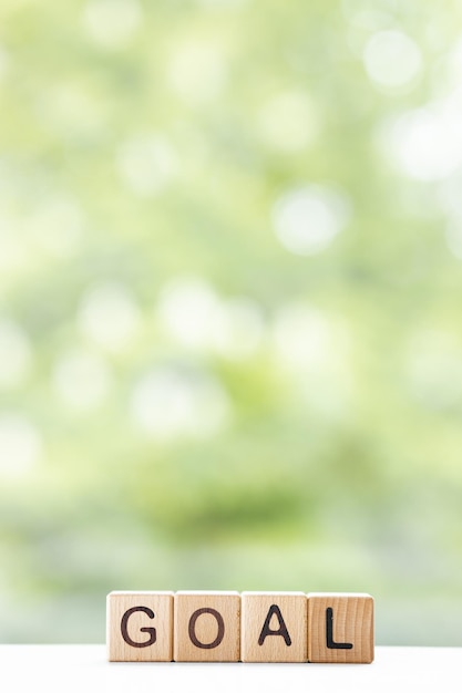 Goal word is written on wooden cubes on a green summer background Closeup of wooden elements