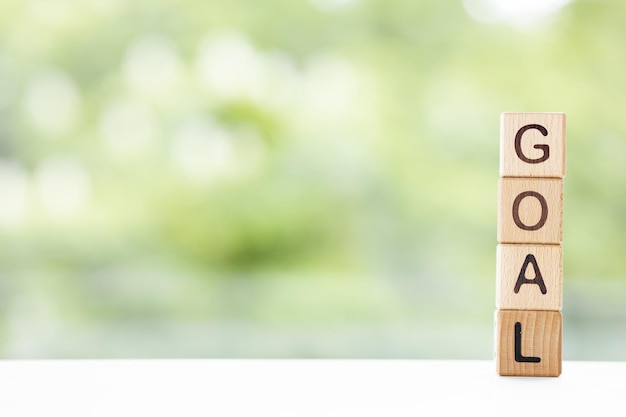 Goal word is written on wooden cubes on a green summer background Closeup of wooden elements