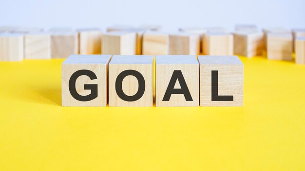 Goal word on wooden blocks lyinging on the yellow table. business concept toy blocks with letters around. selective focus