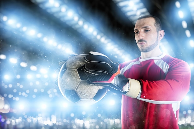 Goalkeeper holds the ball in the stadium during a football game