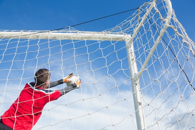 Goalkeeper in red making a save 