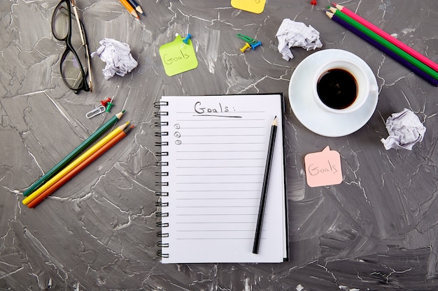 Goals as memo on notebook with idea, crumpled paper, cup of coffee