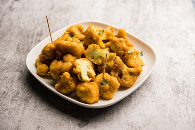 Gobi pakora or Phoolgobi pakoda made using fresh cauliflower dipped chickpea batter and then fried in oil. served with tomato ketchup and mint chutney. selective focus