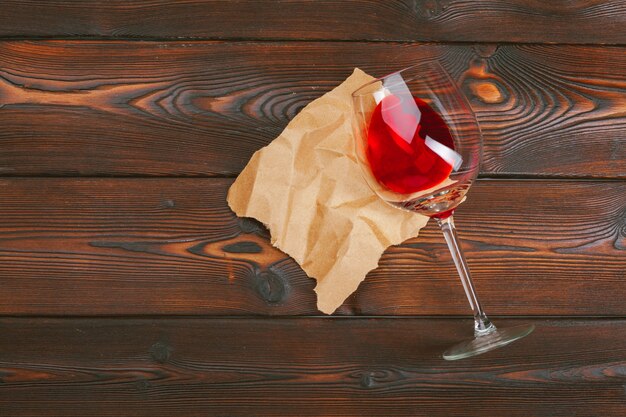 Calice di vino rosso sulla tavola di legno sul fondo di legno della parete