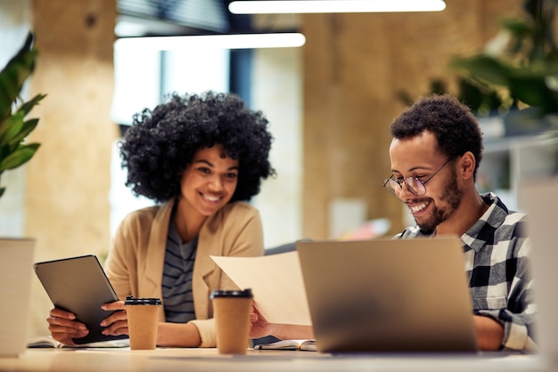 God baan twee jonge, diverse collega's die het verkooprapport analyseren terwijl ze samen op kantoor werken