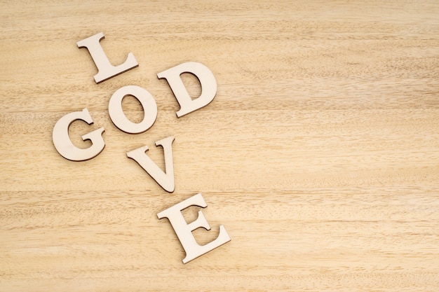 God is liefde concept. woorden vormen een kruis op houten tafel.