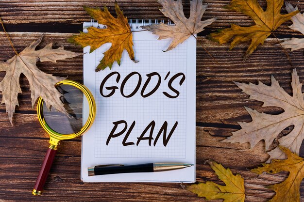 하나님의 계획, 텍스트는 가을 단풍과 오래된 보드가있는 흰색 노트에 기록됩니다.