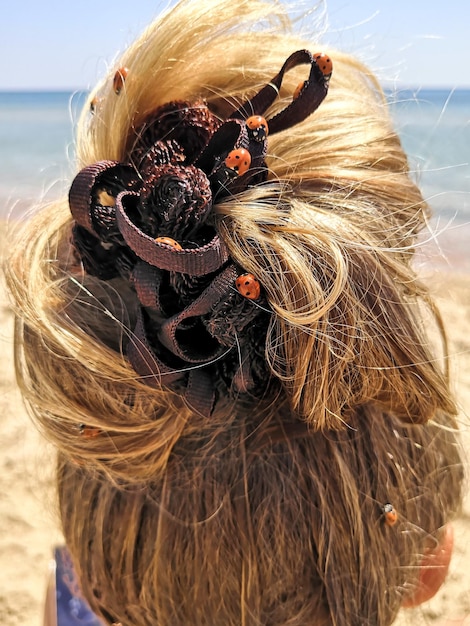 Godbox insect invasion hairstyle of a woman with long blond
hair with a hair clip and many ladybugs