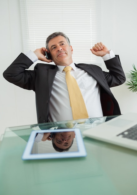 Goed geklede bedrijfsmens die in zijn bureau telefoneert