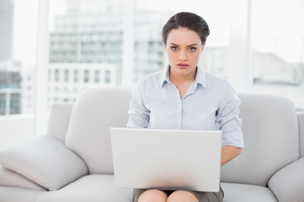 Goed geklede jonge vrouw die laptop thuis met behulp van