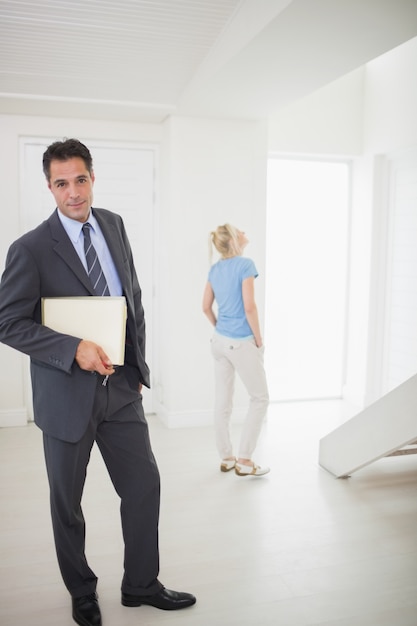 Goed geklede onroerende goederenagent met vage vrouw op achtergrond