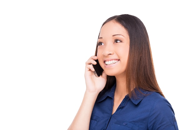 Goed gesprek. Mooie jonge Aziatische vrouw die op de mobiele telefoon praat en glimlacht