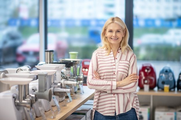 Goed gezind. Blonde vrouwelijke klant die zich in een showroom van consumptiegoederen bevindt en tevreden kijkt