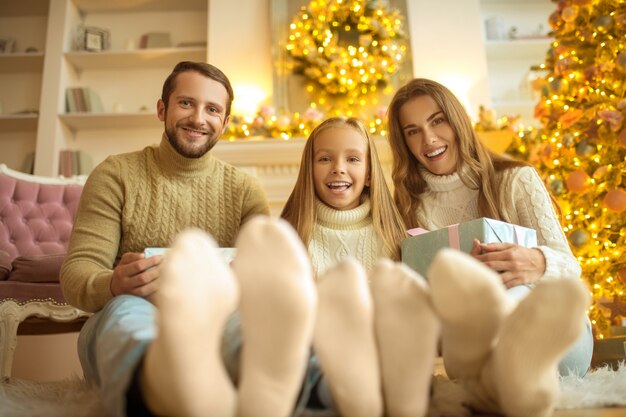 Goed gezind. Leuke familie zittend op de vloer en feestelijk gevoel