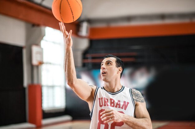 Goed resultaat. Donkerharige basketbalspeler gooide een bal in de ring