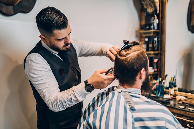 Goed uitziende hipster jonge bebaarde man op bezoek bij kapper in kapperszaak.