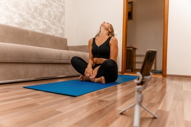 Goed uitziende vrouw van middelbare leeftijd met lang haar fitnessinstructeur in zwarte sportkleding aan het doen