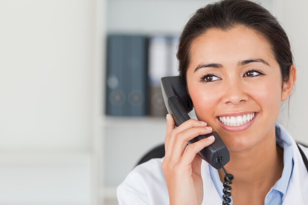 Goed uitziende vrouwelijke arts aan de telefoon en poseren