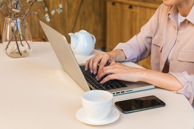 Goede morgen. vrolijk lachende bejaarde senior vrouw die in de keuken staat en haar laptop gebruikt terwijl ze rust na het ontbijt, freelancer die thuis werkt.