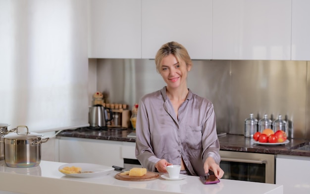 Goedemorgen vrouw die 's ochtends in de keuken zit en koffie drinkt sensuele huisvrouw