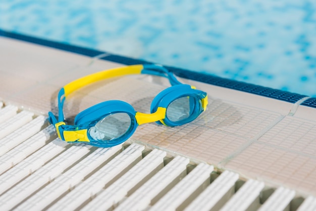 Goggles near swimming pool with blue water