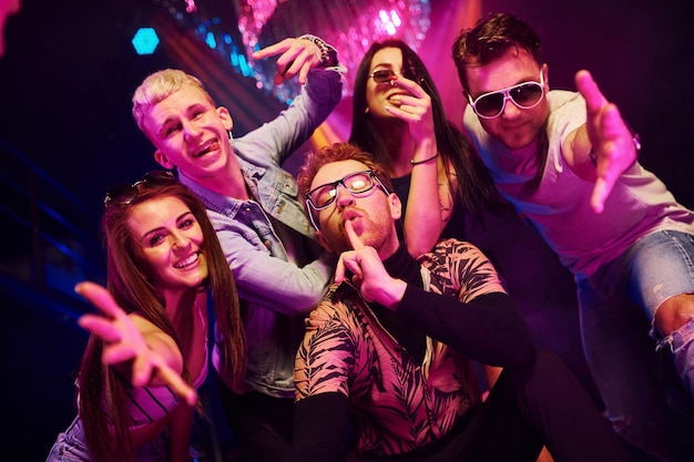 Going crazy and posing for the camera together Young people is having fun in night club with colorful laser lights