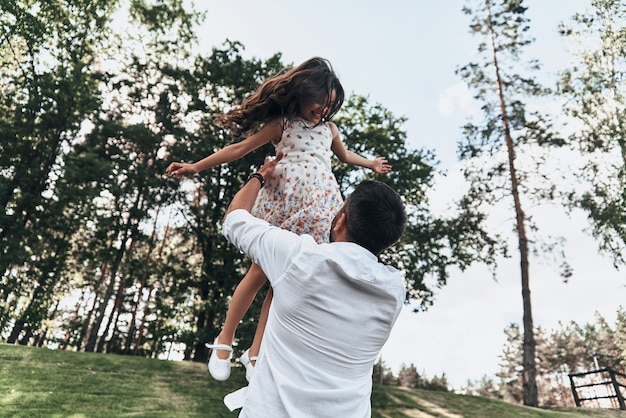 Going crazy together. Young loving father carrying his smiling daughter while spending free time outdoors