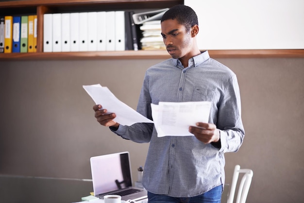 Going over the details of the contract Shot of a handsome young businessman looking over some paperwork in his home office