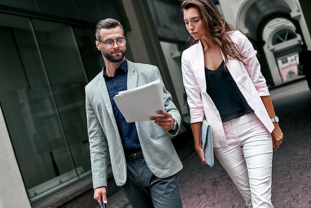 Going to the meeting two young business people walking outside on the city street man