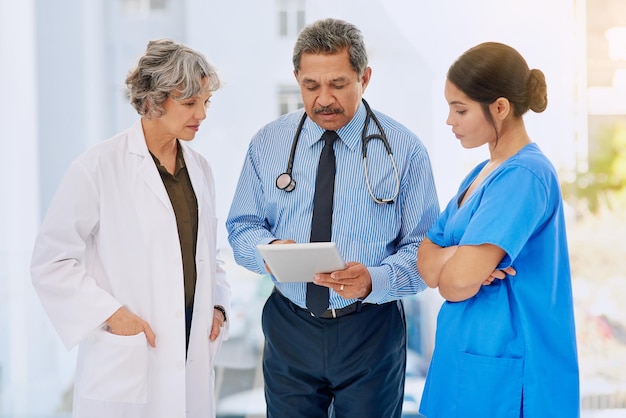 Going over some medical records Shot of three healthcare professionals looking over medical records on a tablet