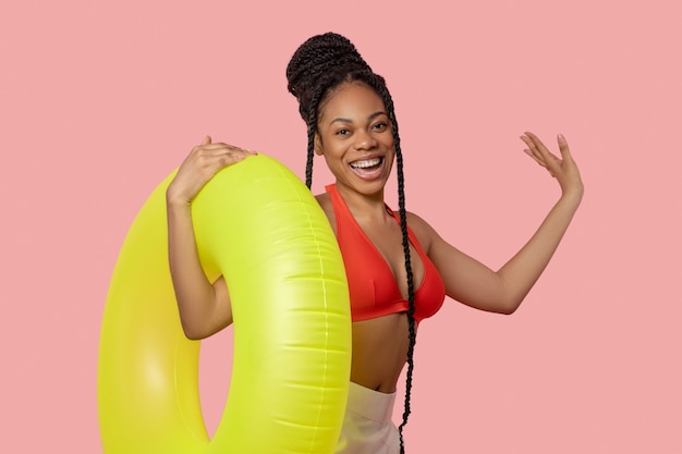 Going to swimming pool. Smiling african american woman holding a yellow tube