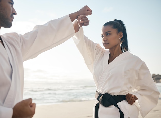 彼らのルーチンを通過します。ビーチで空手を練習している2人の若い武道家のトリミングされたショット。