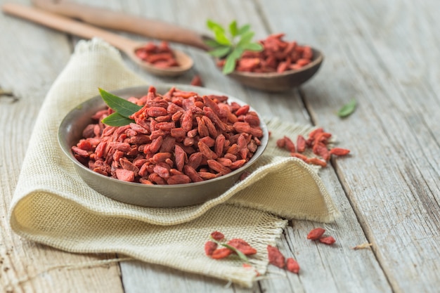 Goji in bowl on wood table. Top view of fresh goji in scoop and bowl.