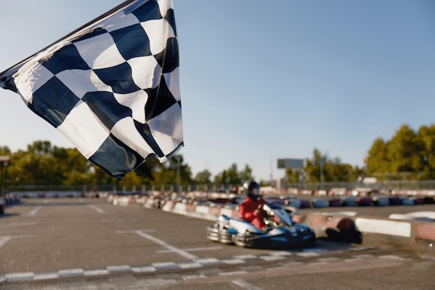 Gokart driver crossing at finish line moving to checkered racing flag