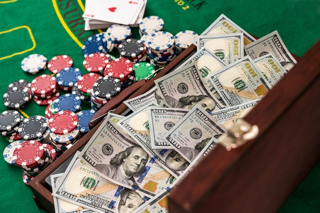 Gokken concept. Kleurrijke pokerfiches met Amerikaanse dollars in houten kist op groene speeltafel.