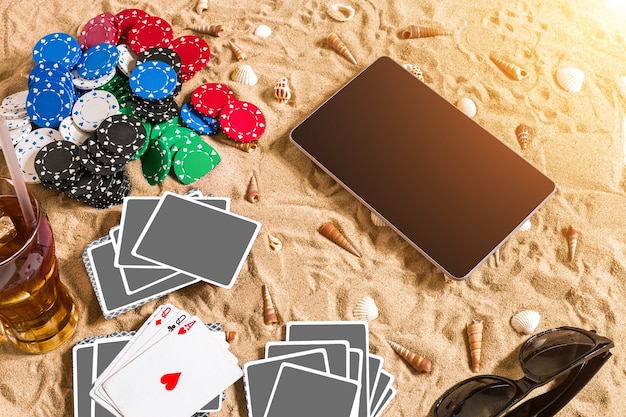 Gokken op vakantieconcept wit zand met schelpen gekleurde pokerfiches en kaarten bovenaanzicht