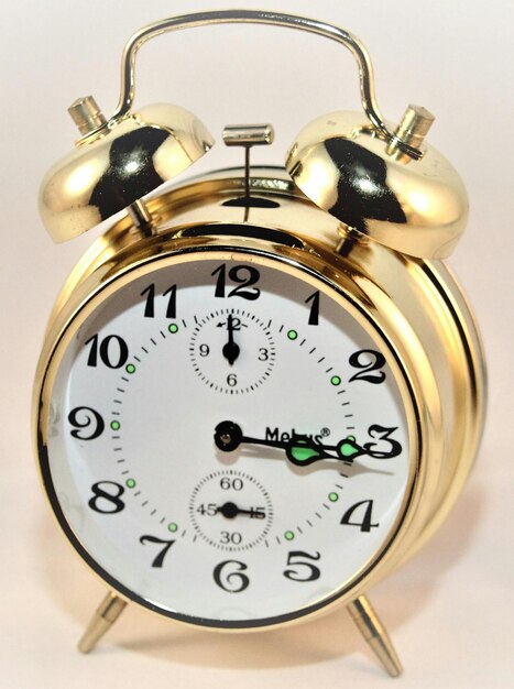 a gold alarm clock with the time as 5  00