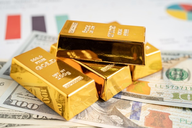 Gold bar on US dollar banknotes money and graph economy finance exchange trade investment concept