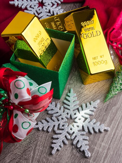 Gold bars as christmas present on wooden table with ornaments.